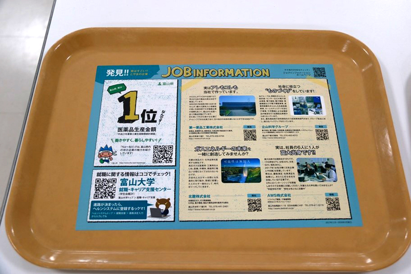 富山県内の企業PR広告を掲載した大学の食堂トレイ
