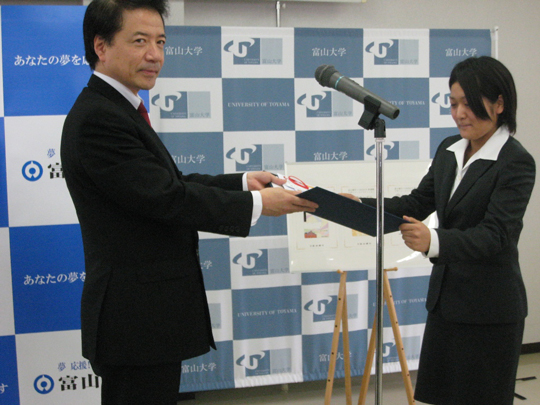 富山銀行 取締役頭取　齊藤 栄吉氏（左）より表彰状を授与される川原 由紀さん