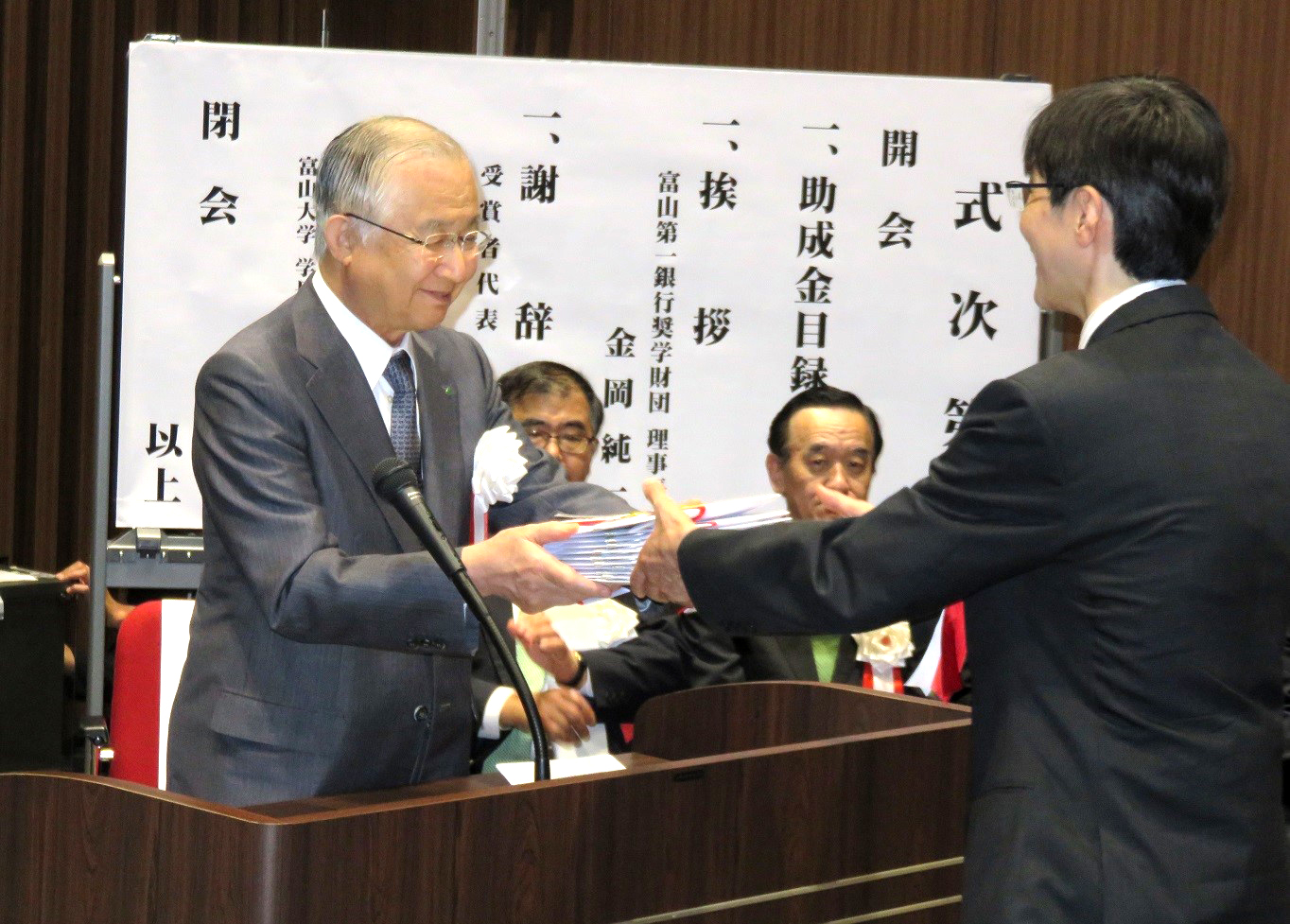 財団の金岡理事長(左)から目録の贈呈を受ける吉田准教授(右)  
