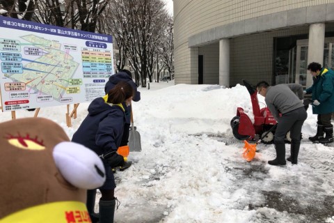 除雪機1台と数人の職員がスコップを手に除雪している写真